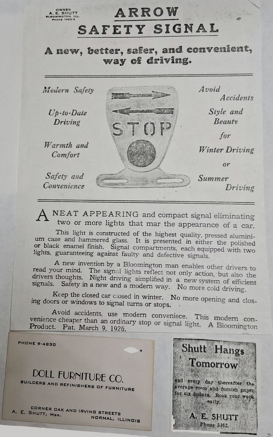 Original 1926 advertising flyer for A.E. Shutt's patented Arrow Safety Signal — an early automobile turn signal — patented March 9, 1926. Shown alongside an original Doll Furniture Co. business card and an "A.E. Shutt: Wallpaper Hanger" newspaper advertisement from his early Bloomington-Normal businesses.