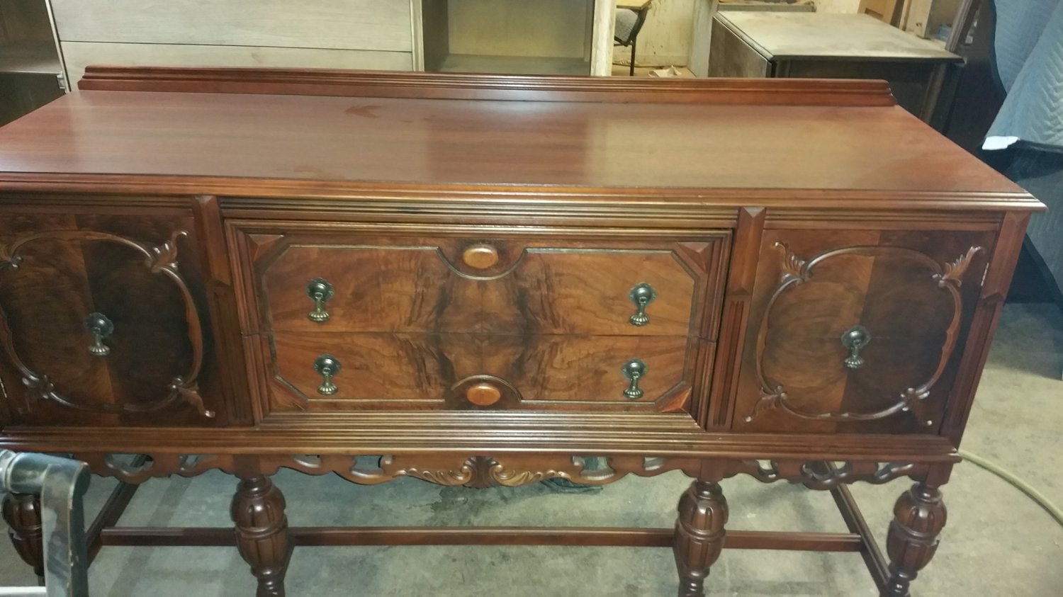 1930s Art Deco walnut buffet with bookmatched burl veneer panels, carved scroll pulls, and turned legs — completely refinished by Doll Furniture Company