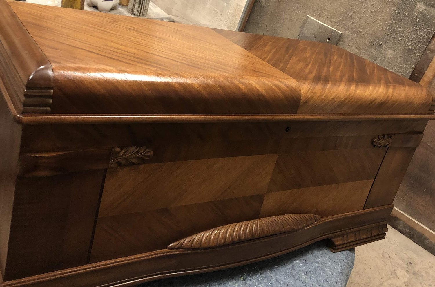 1940s Art Deco waterfall-style cedar chest with bookmatched walnut veneer and carved acanthus leaf accents — refinished to a high gloss by Doll Furniture Company