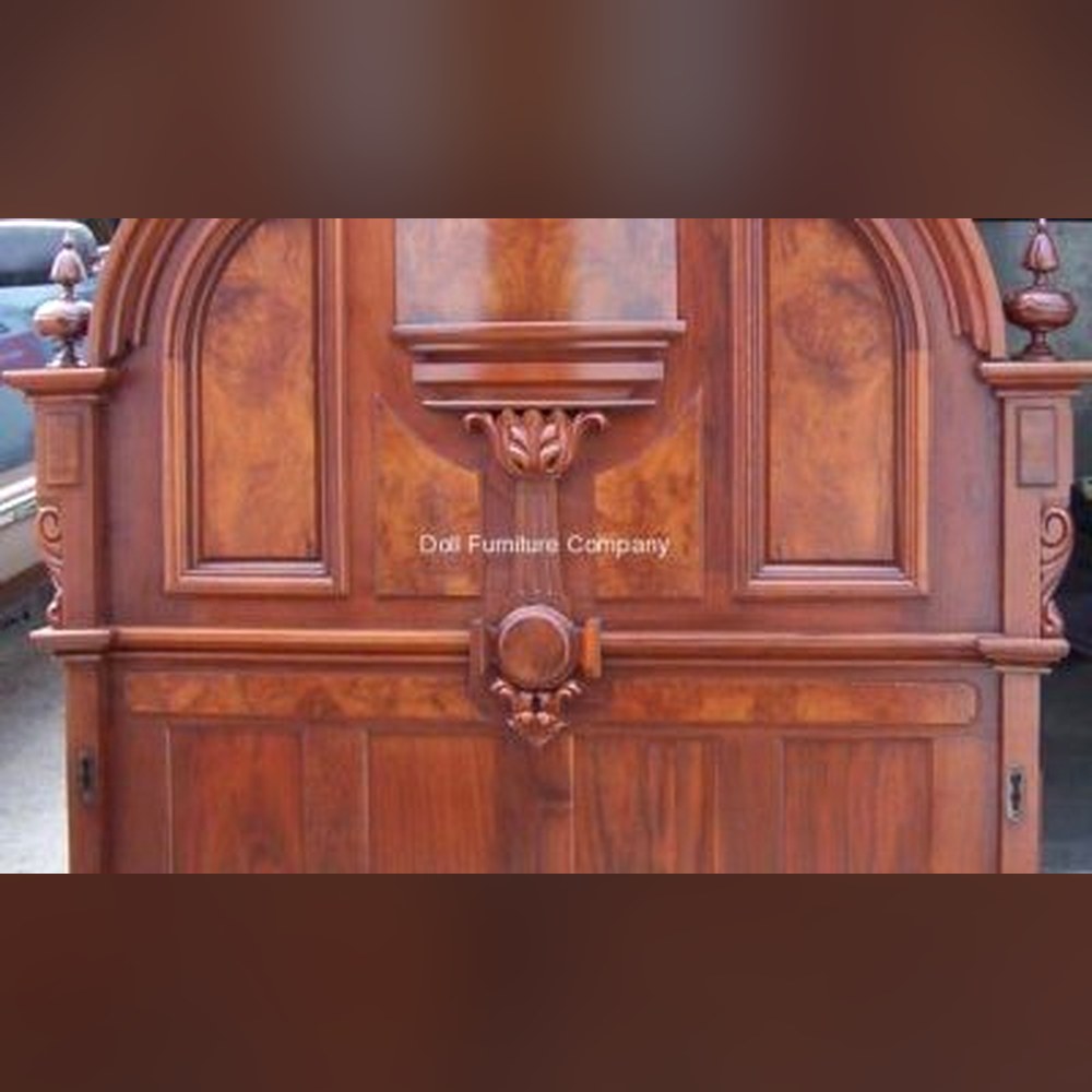 Close-up of early-1800s solid walnut headboard with burl veneer panels, hand-carved finials, and acanthus leaf detail — restored by Doll Furniture Company