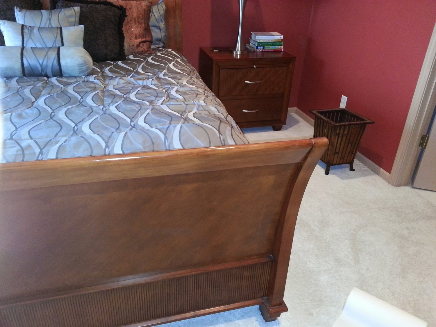 The same cherry sleigh bed footboard after on-site furniture touchup repair by Doll Furniture Company — the white spot is gone, and the rich cherry finish is once again uniform and glossy across the curved footboard